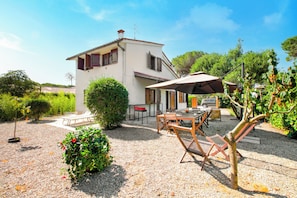 A two-story house with a patio area featuring a table, chairs, and an umbrella. - Villa Janela Escape & Retreat, 30m From the Beach (Orbetello)