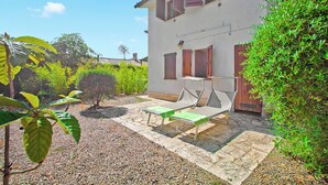 A building with a patio area, a small garden, and a wooden fence.