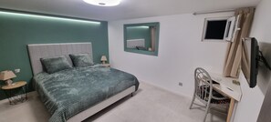 A bedroom with a bed, bedside tables, a mirror, a desk with a chair, and a window. - Ground-floor apartment in a villa complex with a pool (Le Broc)