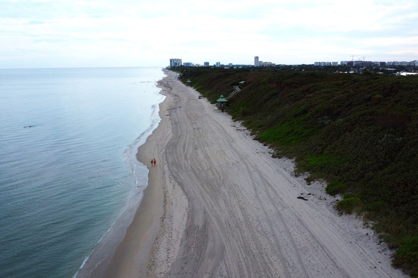 A coastal road with a beach on one side and a cityscape on the other.