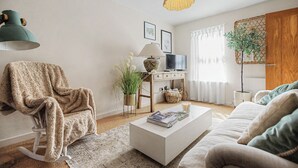 Tunnelmallinen olohuone, jossa on keinutuoli, kirjoja sisältävä sohvapöytä, televisio ja koristeellinen lamppu.