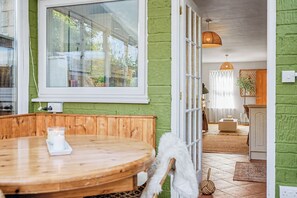 Een kamer met een houten tafel, een witte stoel, een groot raam en een groene wand.