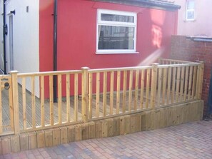 A wooden deck with a railing, a red wall, and a window. - Funky Easton flat with parking (Greenbank)