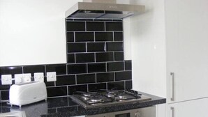 A kitchen with a gas stove, a toaster, and white cabinets. - Funky Easton flat with parking (Greenbank)