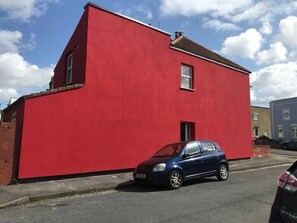 A red building with a single window and a car parked in front. - Funky Easton flat with parking (Greenbank)