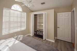 A bedroom with a bed, a walk-in closet, a door, and a ceiling fan. - Fun Hot Tub & Pool Beach Home - Pet Friendly (Port St. Lucie)