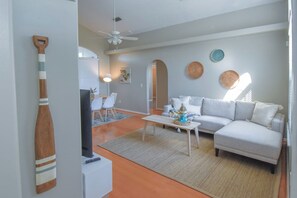 Een woonkamer met een bank, salontafel en een eethoek met stoelen en een tafel.