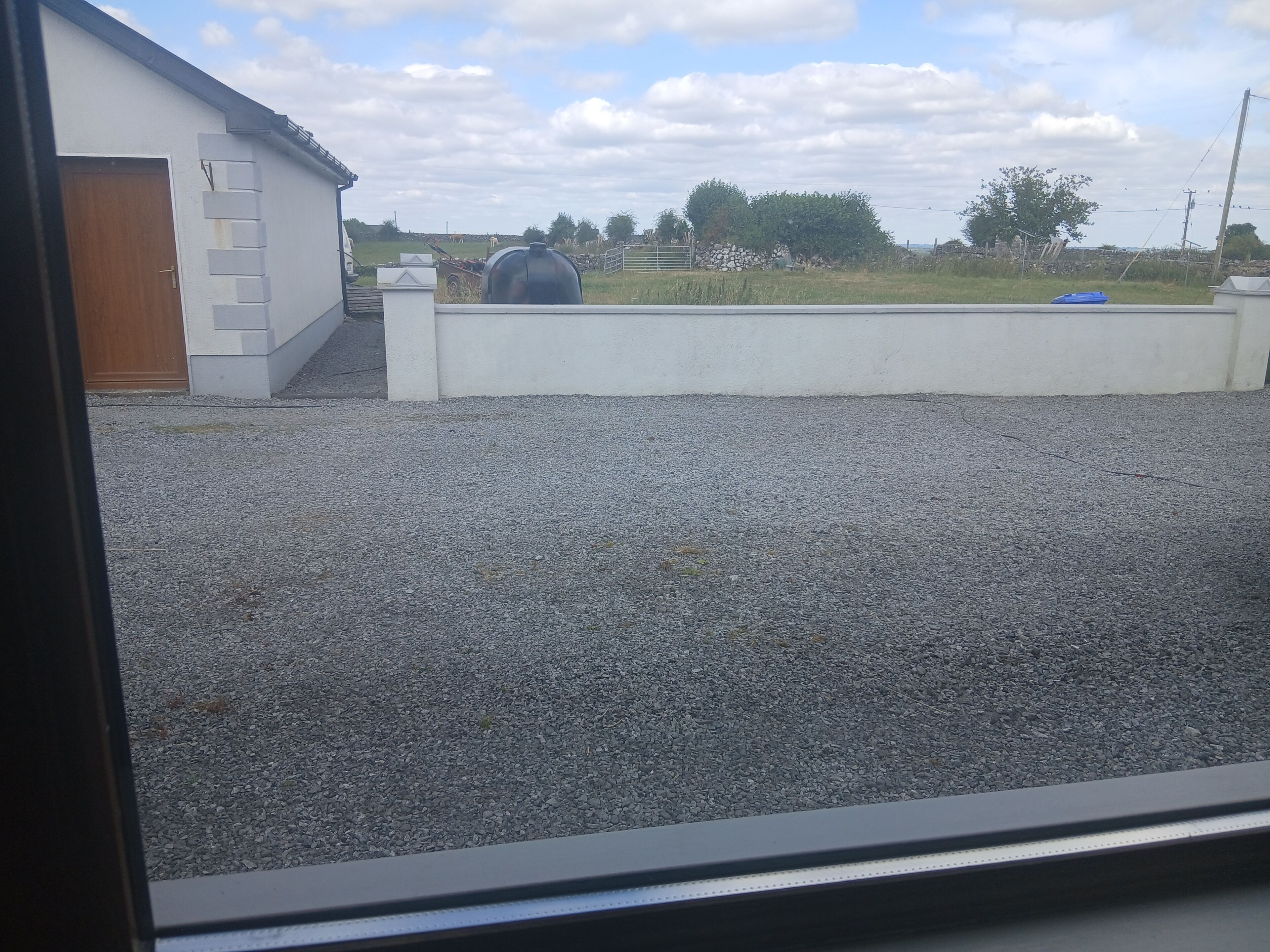 A gravel driveway leading to a white building with a wooden door.