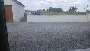 A gravel driveway leading to a white building with a wooden door. - St John s B and B (Lecarrow)