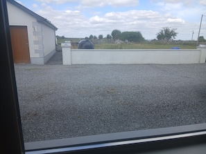 Een grindpad dat leidt naar een wit gebouw met een houten deur.