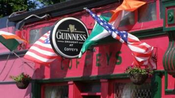 Un bâtiment orné d’une enseigne Guinness, de drapeaux et du mot « COFFEYS » sur la façade.