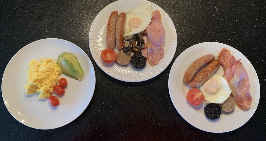 Trois assiettes de nourriture sur un plan de travail sombre.