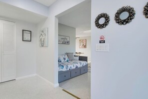 A bedroom with a bed, a nightstand, a wall-mounted mirror, and a door with a louvered window. - 3/2 Heated Pool • Close to Beach • Trails • Golf (Port St. Lucie)