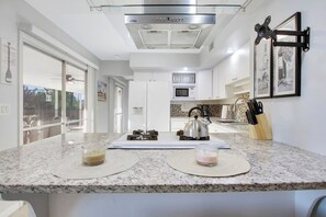A modern kitchen with a gas stove, a kettle, and a knife block.