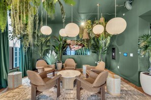 A room with a round wooden table surrounded by wicker chairs, hanging pendant lights, and potted plants. - Botanical Boutique Studio in Miami Downtown (Miami)