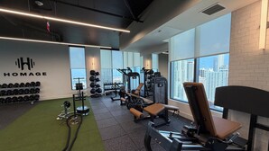 Et fitnessrum med styrketræningsudstyr, en bænk og en vægmonteret squat rack.