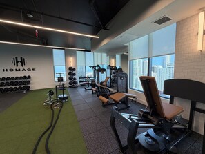 A gym with weightlifting equipment, a bench, and a wall-mounted squat rack. - Botanical Boutique Studio in Miami Downtown (Miami)