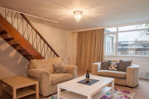 A living room with a staircase, two sofas, a coffee table, and a large window with curtains. - Chippings - Village life in the city. MyCityHaven (Stapleton)