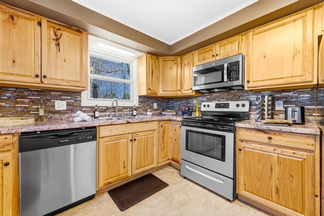 A kitchen with wooden cabinets, a stainless steel dishwasher, a microwave, and an oven.
