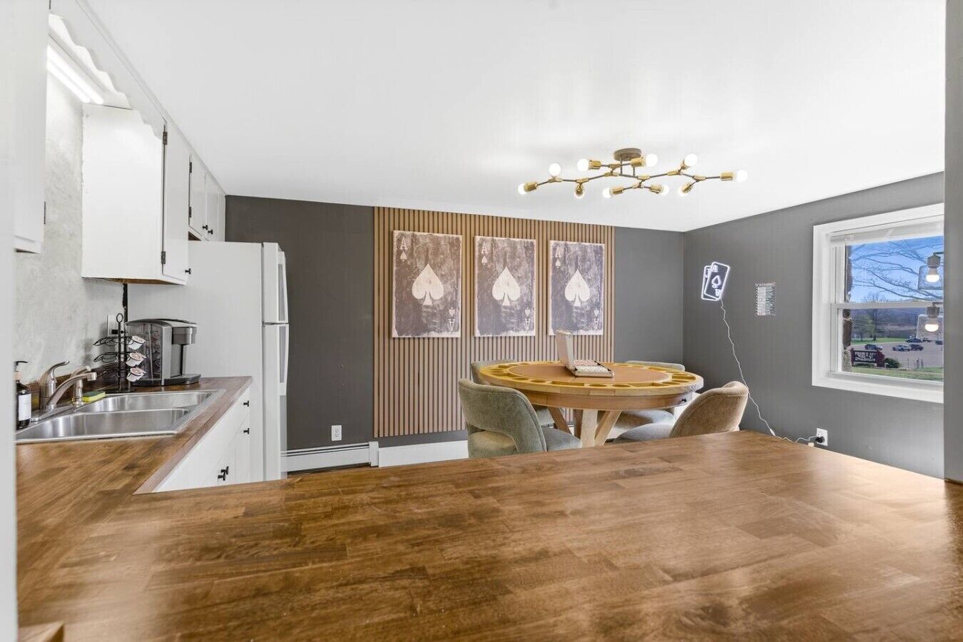 Una cocina moderna con una mesa de comedor de madera, una cafetera y vistas al exterior a través de una ventana.