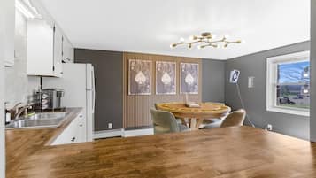 Una cocina moderna con una mesa de comedor de madera, una cafetera y vistas al exterior a través de una ventana.