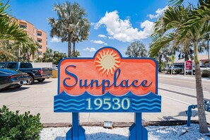 A sign for 'Sunplace 19530' with a sun and waves design. - 2BR | Coastal Condo Steps to Beach, Fully Equipped (Indian Shores)