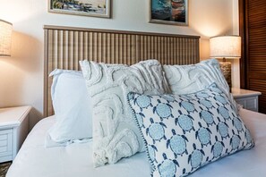 A hotel room with a bed, a headboard, and two bedside tables. - 2BR | Coastal Condo Steps to Beach, Fully Equipped (Indian Shores)