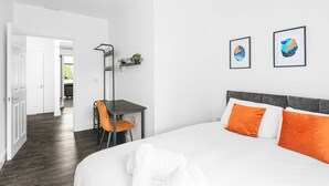 Ett hotellrum med en säng, ett skrivbord och två inramade konstverk på väggen.