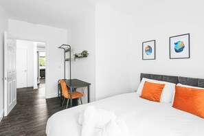 A hotel room with a bed, a desk, and two framed artworks on the wall. - Garden View by MyCityHaven (Redland)