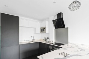 A modern kitchen with a built-in microwave, stainless steel appliances, and a marble countertop. - Garden View by MyCityHaven (Redland)