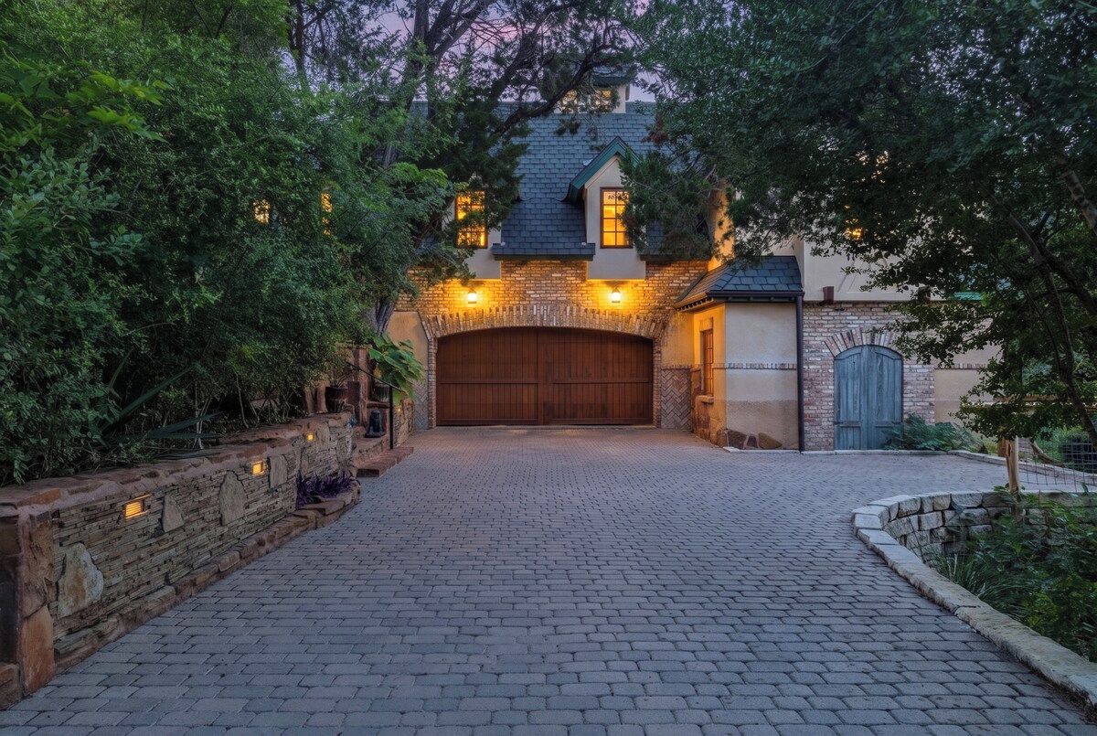 A house with a brick driveway leading to a wooden garage door.