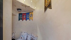 Un dormitorio con una cama, almohadas, un ventilador de techo y una pared decorada con banderas.