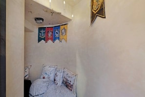 Ein Schlafzimmer mit einem Bett, Kissen, einem Deckenventilator und einer Wand mit Flaggen.