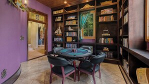 Una habitación con una mesa redonda y sillas, rodeada de estanterías llenas de libros y objetos decorativos.