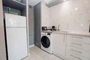 A compact kitchen with a built-in washing machine, a small sink, and a white refrigerator. - Spacious Oxford Apartment | Near JR Hospital & (Headington)