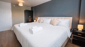 A hotel room with a large bed, bedside lamps, a wardrobe, and a door. - Spacious Oxford Apartment | Near JR Hospital & (Headington)