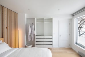Un dormitorio con cama, armario con espacio para colgar y ventana con vistas a árboles.
