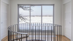 Una habitación con un ventanal grande, vistas a un paisaje nevado y una escalera de caracol.