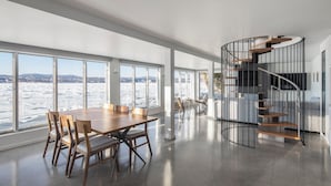 Un interior espacioso con una gran mesa de comedor, una escalera de caracol y vistas a un paisaje nevado.