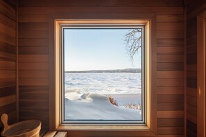 Una cabaña de madera con un ventanal grande que da a un paisaje nevado.