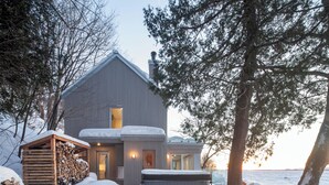 Una cabaña con una terraza grande, un jacuzzi y un paisaje cubierto de nieve.