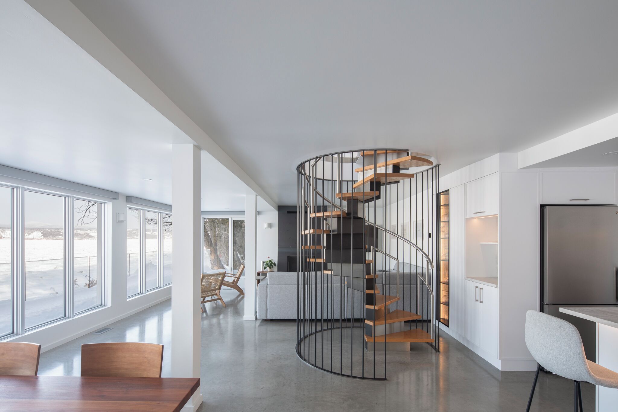 A modern interior with a spiral staircase, a dining area, and a kitchen.