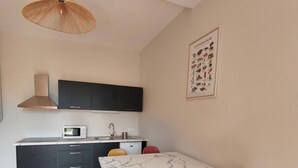 Una cocina moderna con comedor, que incluye una mesa de mármol blanco, armarios negros y una lámpara colgante.