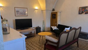Un soggiorno con televisore, divano, poltrona, pavimento decorato e una porta con un elemento decorativo sulla sommità.