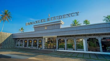 A hotel entrance with a sign, palm trees, and a stone facade.