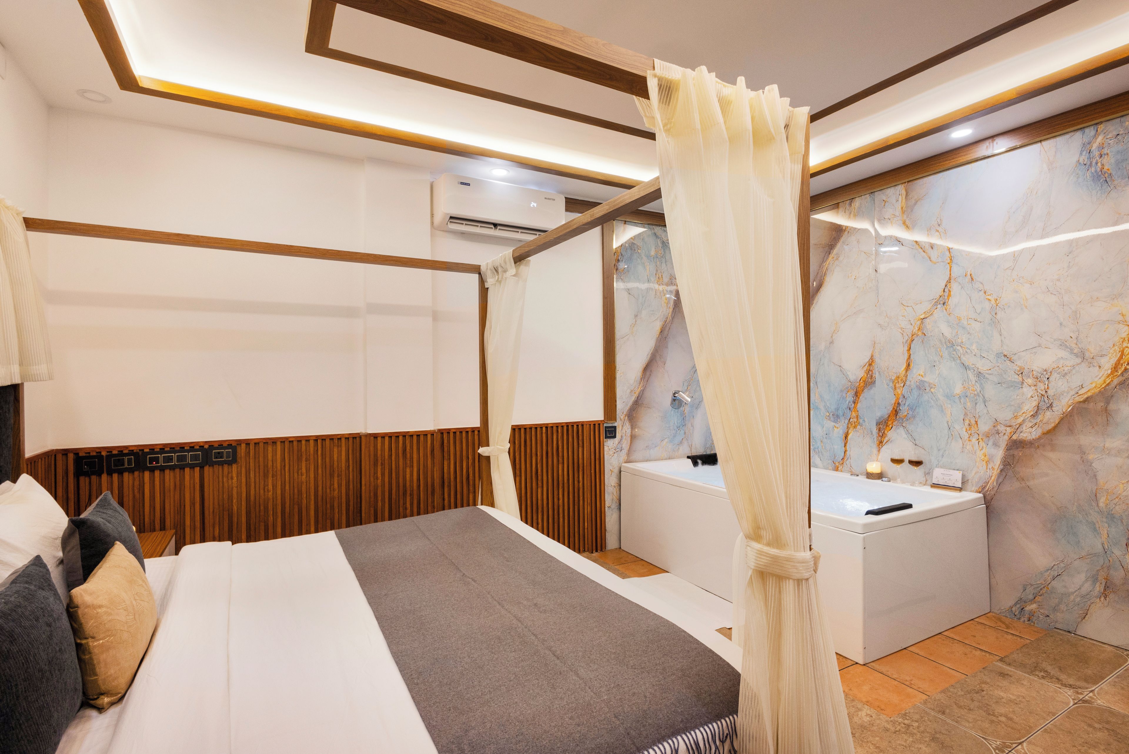 Habitación de hotel con cama, baño con bañera, paneles de madera y pared de mármol.