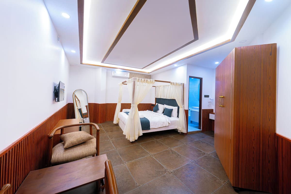 Une chambre à coucher avec un lit à baldaquin, une armoire en bois, une chaise et un bureau.