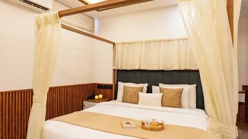 Habitación de hotel con cama con dosel, paneles de madera, mesita de noche con lámpara y mesita de noche con teléfono y velas.