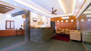 Un espace d’accueil avec un comptoir en pierre, un ventilateur de plafond, un canapé et un tapis rouge.
