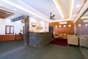 Un espace d’accueil avec un comptoir en pierre, un ventilateur de plafond, un canapé et un tapis rouge.